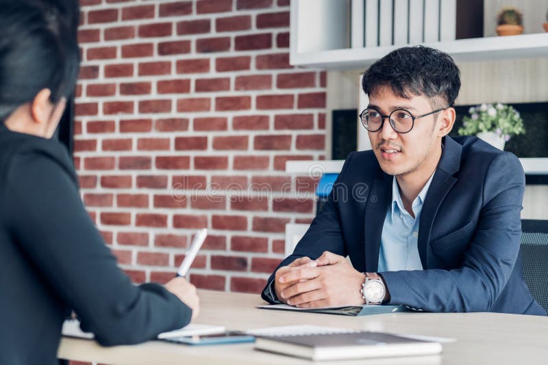 Hombre de negocios joven y empresaria asiáticos que hablan del acuerdo del negocio en la mesa de reuniones en oficina moderna Soc fotografía de archivo Hombre de negocios joven y empresaria asiáticos que hablan del acuerdo del negocio en la mesa de reuniones en oficina moderna Soc fotografía de archivo