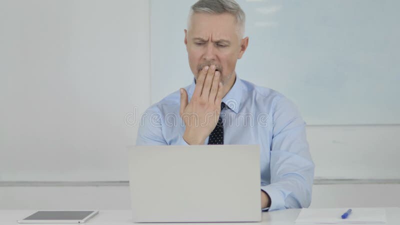 Hombre de negocios mayor cansado Yawning en el trabajo