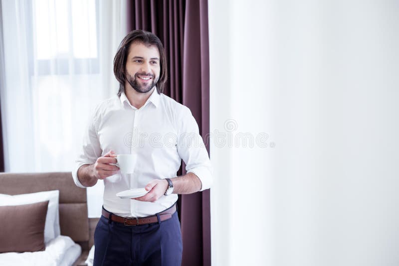 Hombre de negocios positivo alegre que disfruta de su bebida de la mañana imagen de archivo Hombre de negocios positivo alegre que disfruta de su bebida de la mañana imagen de archivo