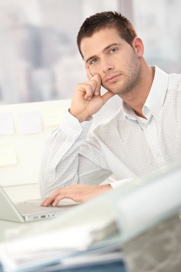 Hombre de negocios preocupado que se sienta en el escritorio imagen de archivo Hombre de negocios preocupado que se sienta en el escritorio imagen de archivo