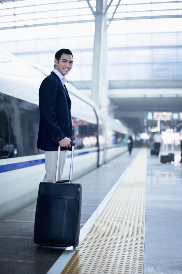 Hombre de negocios que defiende con una maleta en la plataforma del ferrocarril un tren de alta velocidad en Pekín imagen de archivo libre de regalías Hombre de negocios que defiende con una maleta en la plataforma del ferrocarril un tren de alta velocidad en Pekín imagen de archivo libre de regalías
