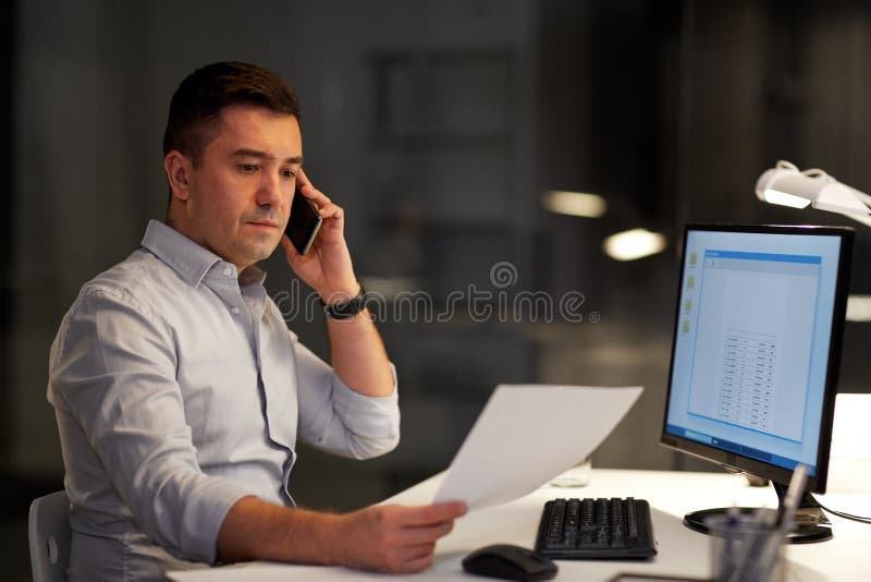Hombre de negocios que invita a sartphone en la oficina de la noche fotografía de archivo libre de regalías Hombre de negocios que invita a sartphone en la oficina de la noche fotografía de archivo libre de regalías