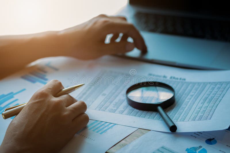 Businessman looking through a magnifying glass to documents. Business assessment and audit. Magnifying glass on a financial report. Close-up Of Businessperson Checking Bills With Magnifying Glass.Concept of search. Businessman looking through a magnifying glass to documents. Business assessment and audit. Magnifying glass on a financial report. Close-up Of Businessperson Checking Bills With Magnifying Glass.Concept of search.