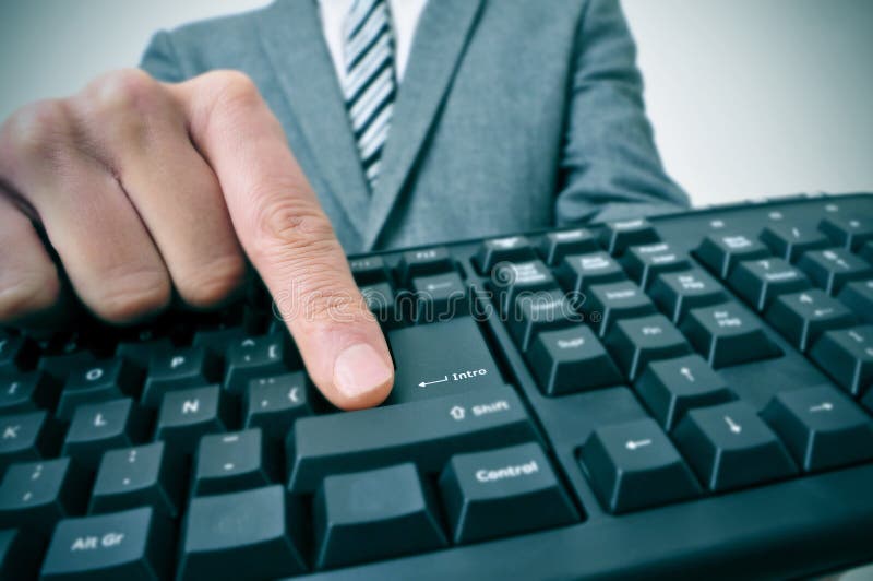 Hombre de negocios que pulsa la tecla de la introducción de un teclado de ordenador imagenes de archivo Hombre de negocios que pulsa la tecla de la introducción de un teclado de ordenador imagenes de archivo