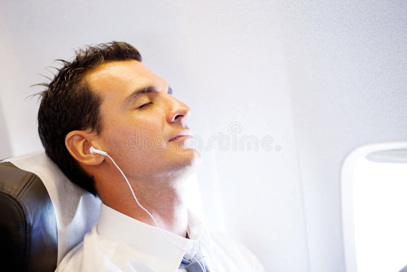 Hombre de negocios que se relaja en el aeroplano foto de archivo Hombre de negocios que se relaja en el aeroplano foto de archivo