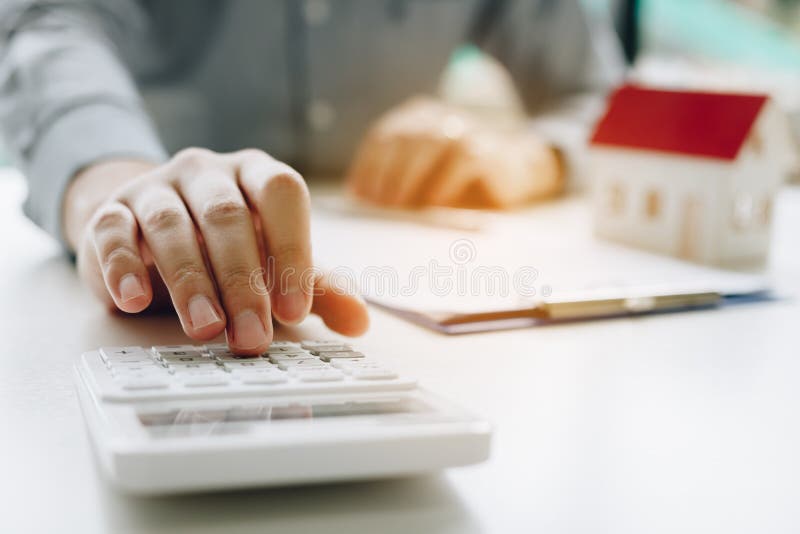 Hombre de negocios que usa la calculadora para calcular el presupuesto sobre hipoteca del contrato de la casa en el cuarto de la