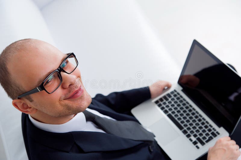Hombre de negocios sonriente joven usando el ordenador portátil fotografía de archivo libre de regalías Hombre de negocios sonriente joven usando el ordenador portátil fotografía de archivo libre de regalías