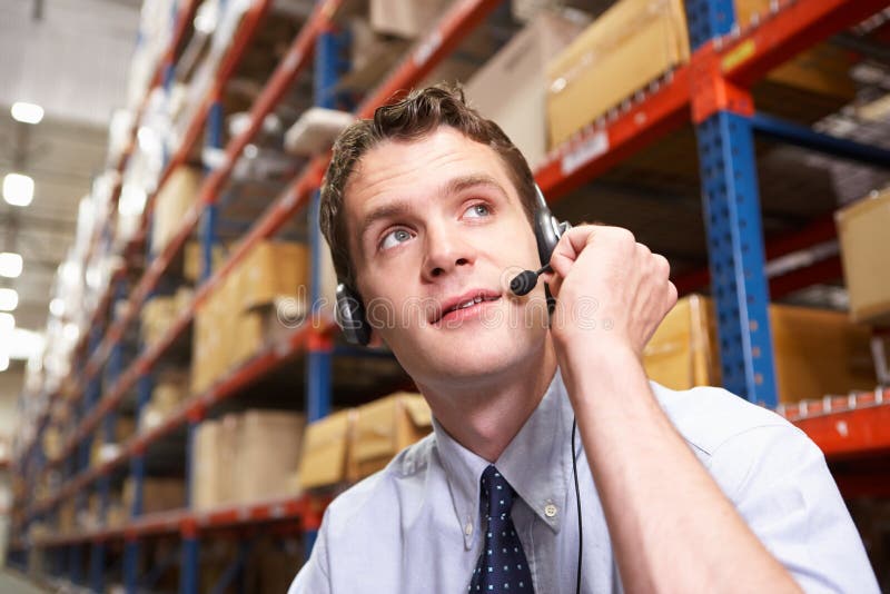 Hombre de negocios usando las auriculares en la distribución Warehouse