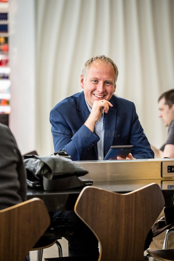 Hombre de negocios usando su tableta en el aeropuerto imágenes de archivo libres de regalías Hombre de negocios usando su tableta en el aeropuerto imágenes de archivo libres de regalías
