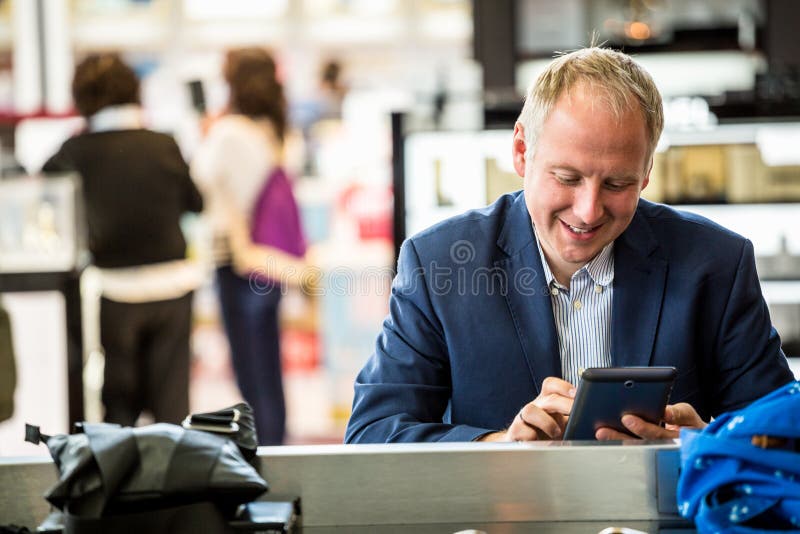 Hombre de negocios usando su tableta en el aeropuerto fotos de archivo Hombre de negocios usando su tableta en el aeropuerto fotos de archivo