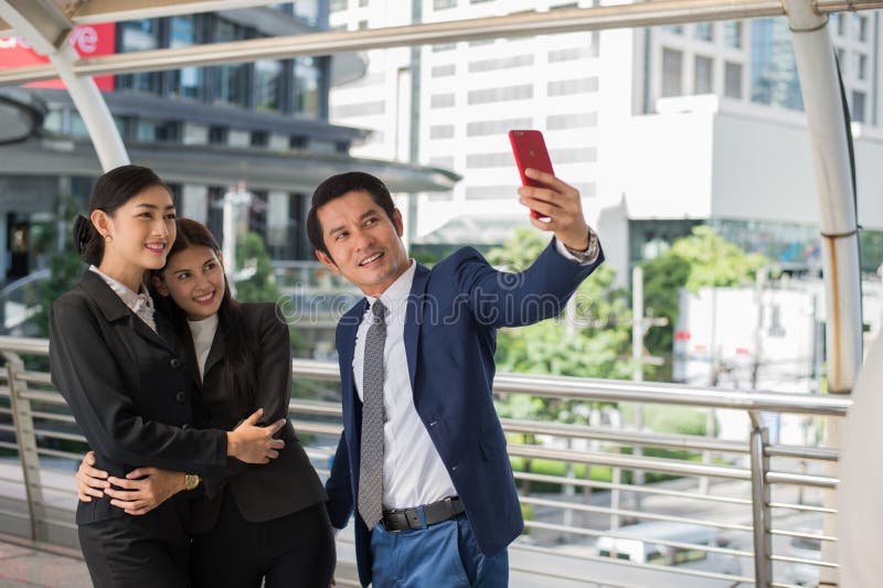 Hombre de negocios y empresaria que toman un selfie por smartphone imagen de archivo libre de regalías Hombre de negocios y empresaria que toman un selfie por smartphone imagen de archivo libre de regalías