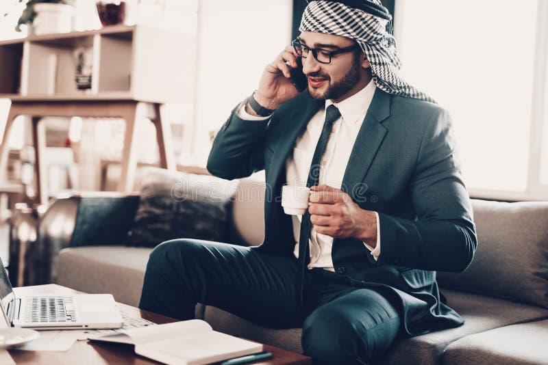 Hombre de negocios árabe que habla en el teléfono con café imagen de archivo