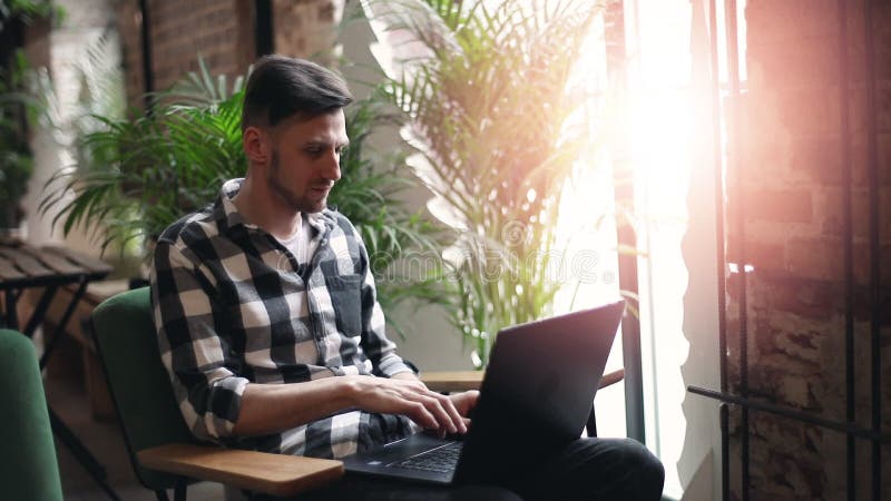 Hombre del empresario con el ordenador portátil cerca de la ventana