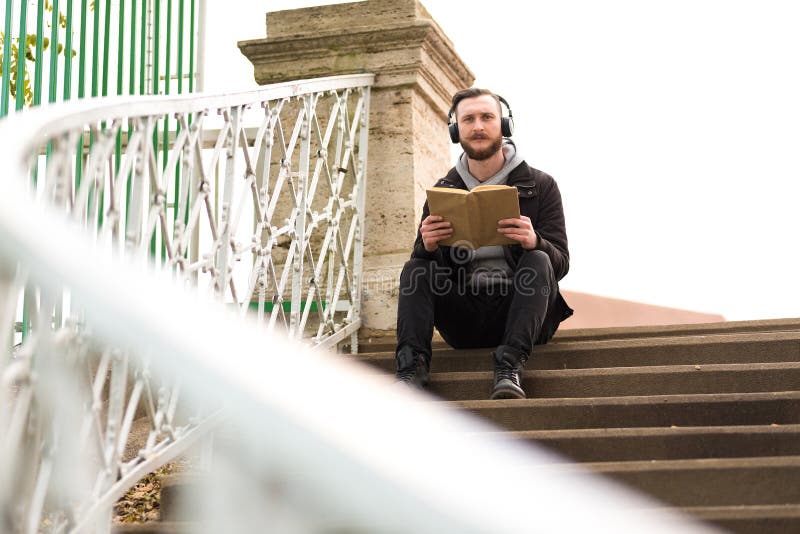 Hombre del inconformista que se sienta en las escaleras y la lectura fotos de archivo Hombre del inconformista que se sienta en las escaleras y la lectura fotos de archivo