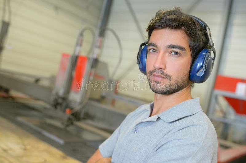 Hombre del retrato en orejeras que llevan de la fábrica imagen de archivo libre de regalías Hombre del retrato en orejeras que llevan de la fábrica imagen de archivo libre de regalías