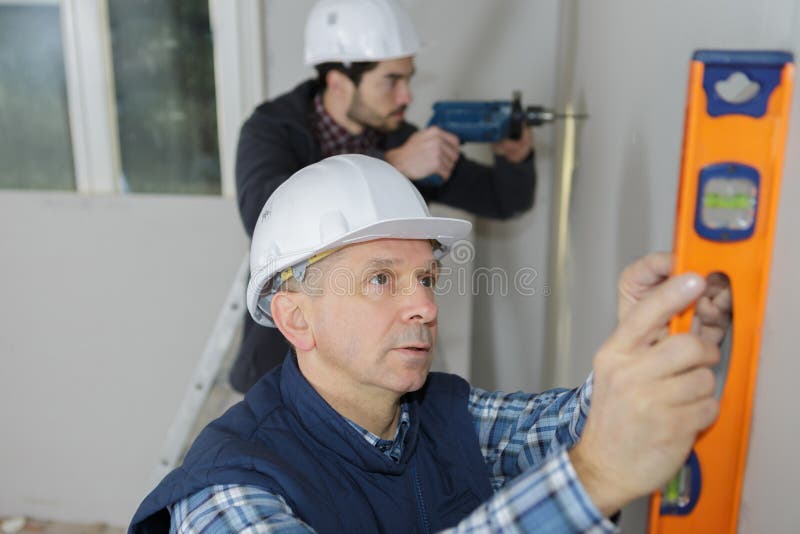 Hombre del trabajador que usa el nivel de alcohol foto de archivo libre de regalías Hombre del trabajador que usa el nivel de alcohol foto de archivo libre de regalías