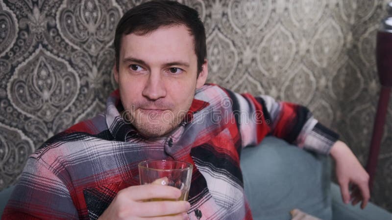 Hombre disfrutando de una bebida mientras se sienta cómodamente en una acogedora sala de estar almacen de video