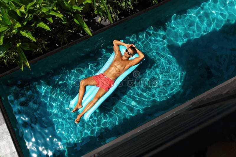 Hombre el vacaciones de verano Piscina modelo masculina de Tanning In Swimming fotografía de archivo libre de regalías Hombre el vacaciones de verano Piscina modelo masculina de Tanning In Swimming fotografía de archivo libre de regalías