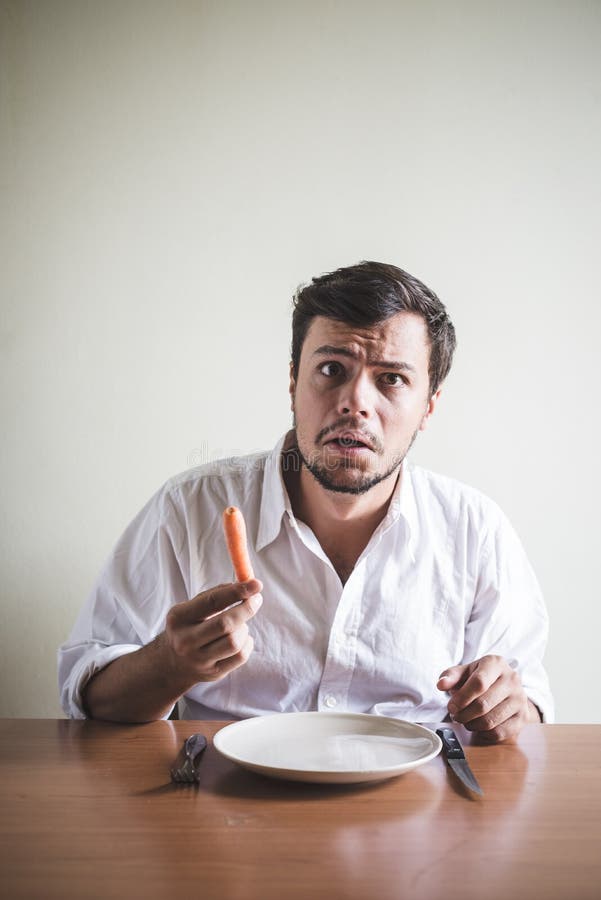 Hombre Elegante Joven Con La Camisa Blanca Que Come La Zanahoria Imagen