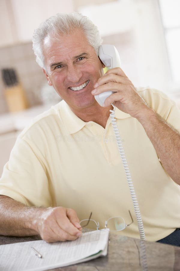 Hombre en cocina en la sonrisa del teléfono imágenes de archivo libres de regalías Hombre en cocina en la sonrisa del teléfono imágenes de archivo libres de regalías