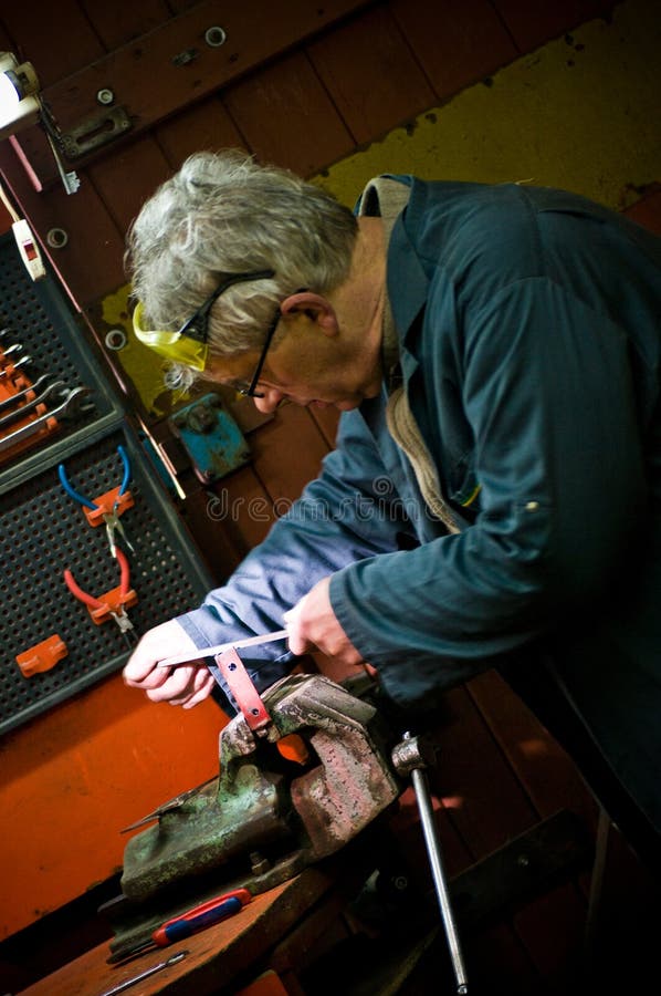 Hombre en el taller del metal que trabaja en el pedazo de metal imagenes de archivo Hombre en el taller del metal que trabaja en el pedazo de metal imagenes de archivo