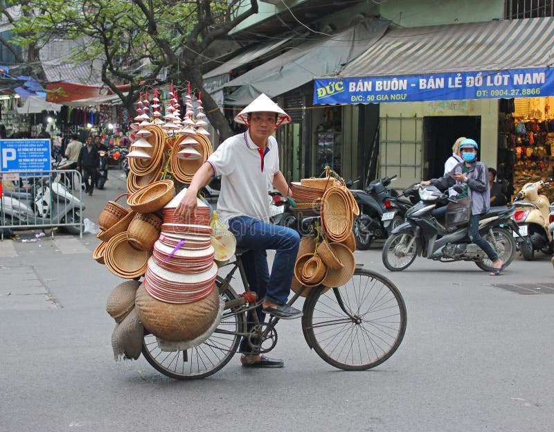Hombre en la bicicleta que vende los sombreros de Hanoi foto de archivo Hombre en la bicicleta que vende los sombreros de Hanoi foto de archivo