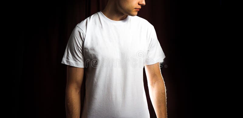 Hombre en la camiseta blanca en blanco, en un fondo negro, mofa para arriba, espacio libre foto de archivo libre de regalías Hombre en la camiseta blanca en blanco, en un fondo negro, mofa para arriba, espacio libre foto de archivo libre de regalías