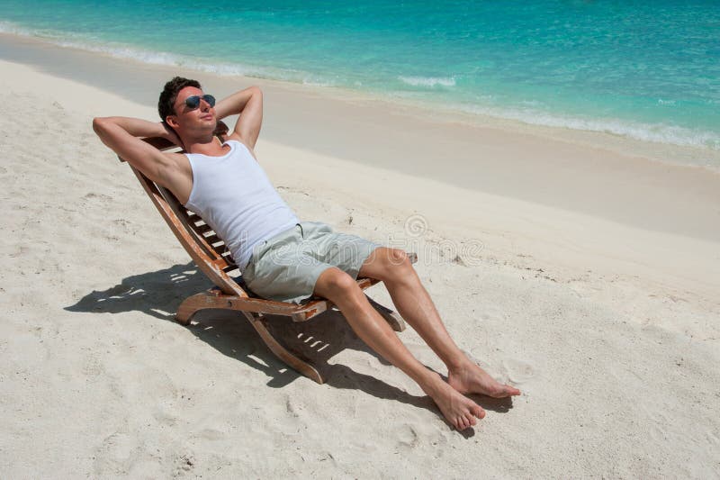 Hombre En Silla Que Toma El Sol En La Playa Cerca Del Océano Imagen de