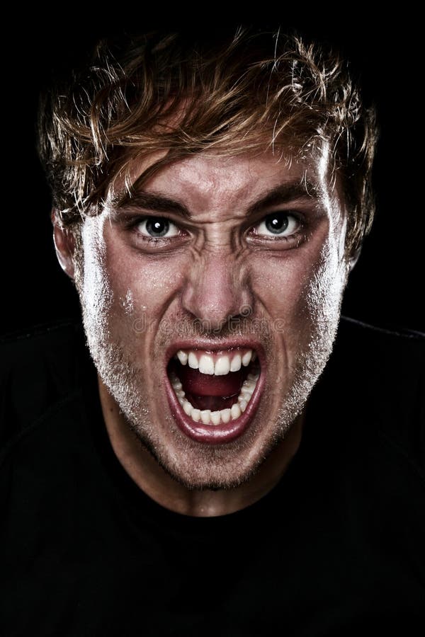 Man screaming angry aggressive at camera on black background. Young Caucasian mad male model. Man screaming angry aggressive at camera on black background. Young Caucasian mad male model.