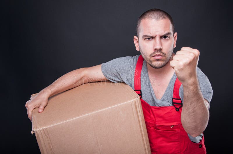 Hombre enojado del motor que sostiene la caja que muestra el puño fotos de archivo Hombre enojado del motor que sostiene la caja que muestra el puño fotos de archivo