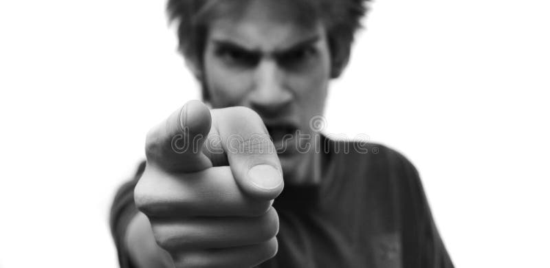 Angry young man pointing his finger with rage at the camera. The hand is selectively in focus and there is white isolated copyspace on both sides of him. Angry young man pointing his finger with rage at the camera. The hand is selectively in focus and there is white isolated copyspace on both sides of him.