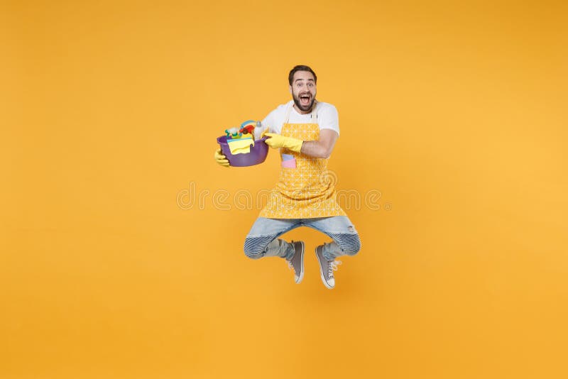 Hombre excitado ama de casa en guantes de manzana sostener botellas detergentes lavadoras lavadoras haciendo tareas domésticas ais imagen de archivo