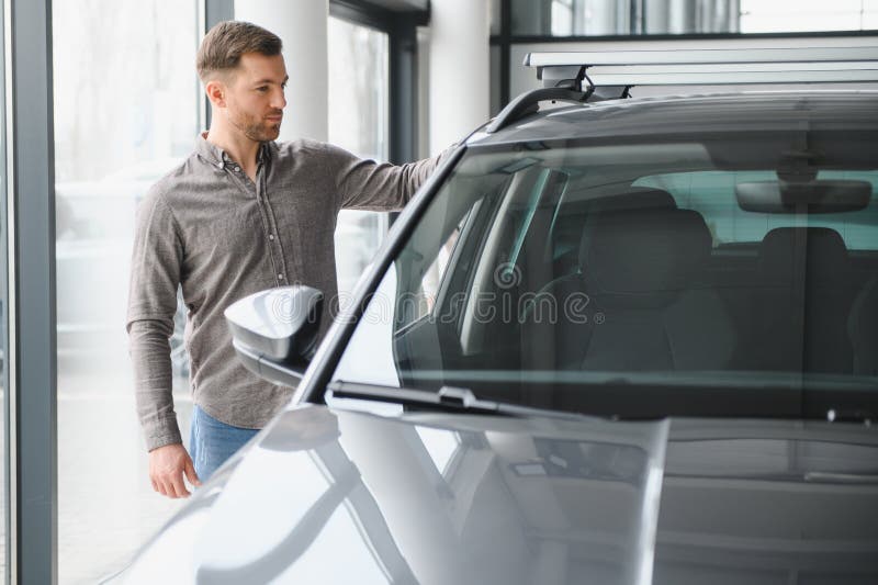 Hombre explorando las opciones de los autos en la moderna sala de espectáculos imagenes de archivo