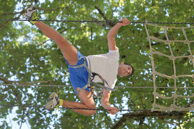 Hombre feliz en el parque extremo de la cuerda con mosquetones imagenes de archivo Hombre feliz en el parque extremo de la cuerda con mosquetones imagenes de archivo