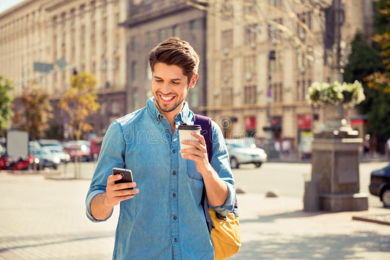Hombre feliz paseando por la ciudad y escribiendo sms