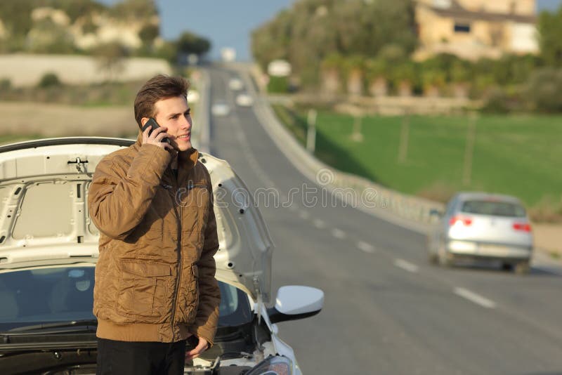 Hombre feliz que llama la ayuda del borde de la carretera para su coche de la avería