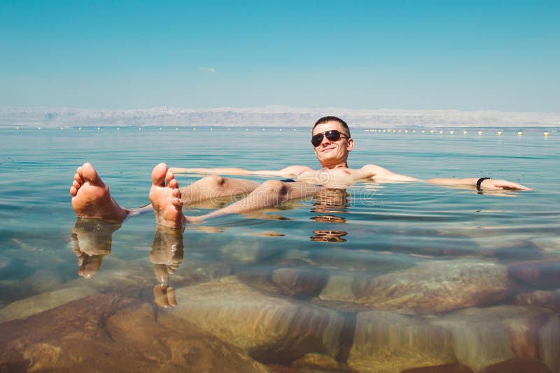 Hombre feliz que se relaja en el mar muerto del agua Reconstrucción del turismo, concepto sano de la forma de vida Copie el espac fotografía de archivo Hombre feliz que se relaja en el mar muerto del agua Reconstrucción del turismo, concepto sano de la forma de vida Copie el espac fotografía de archivo