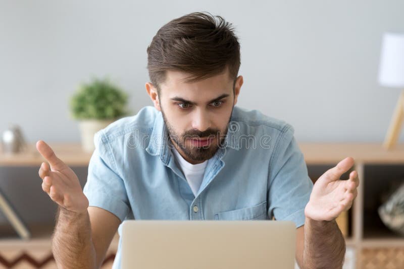 Hombre frustrado que mira la pantalla de ordenador que se sienta en el escritorio imágenes de archivo libres de regalías