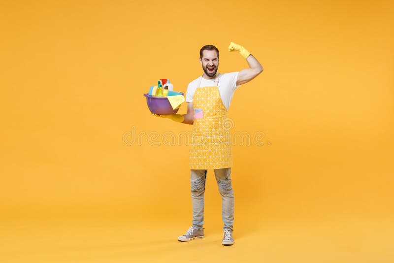 Hombre fuerte esposo de la casa en guantes de apron sostener botellas detergentes lavadoras de lavado de cuencas haciendo tareas d imagenes de archivo