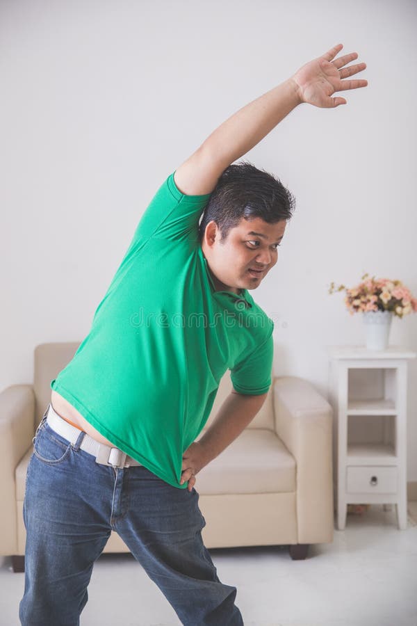 Hombre gordo que hace un cierto ejercicio en casa imagen de archivo Hombre gordo que hace un cierto ejercicio en casa imagen de archivo