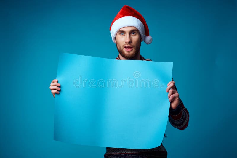 Hombre Guapo Con Sombrero De Santa Sosteniendo Un Cartel De Fondo Azul  Feriado Foto de archivo - Imagen de cartel, copia: 230425566