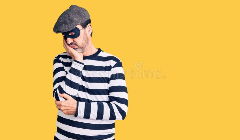 Hombre guapo de mediana edad con máscara ladrón pensando cansado y aburrido con problemas de depresión con los brazos cruzados imagen de archivo