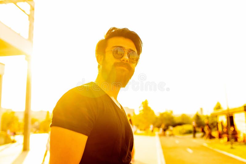 Hombre guapo en gafas de sol en el parque de verano en luces de oro puestas al sol fotos de archivo libres de regalías