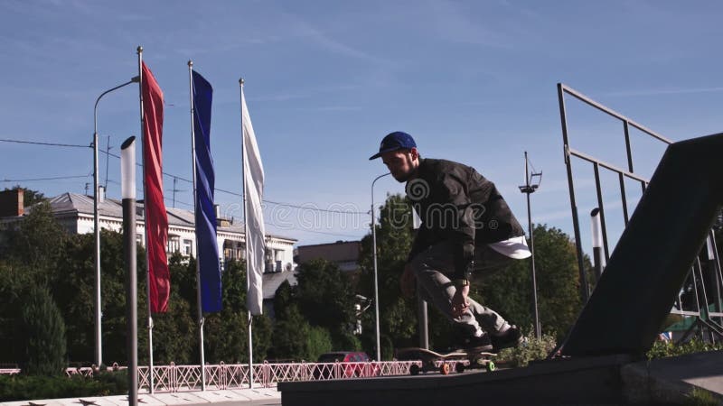 Hombre guapo que salta en un monopatín. Un joven que disfruta de la ciudad que se mueve en un monopatín. Recreación de la ciudad e almacen de metraje de vídeo