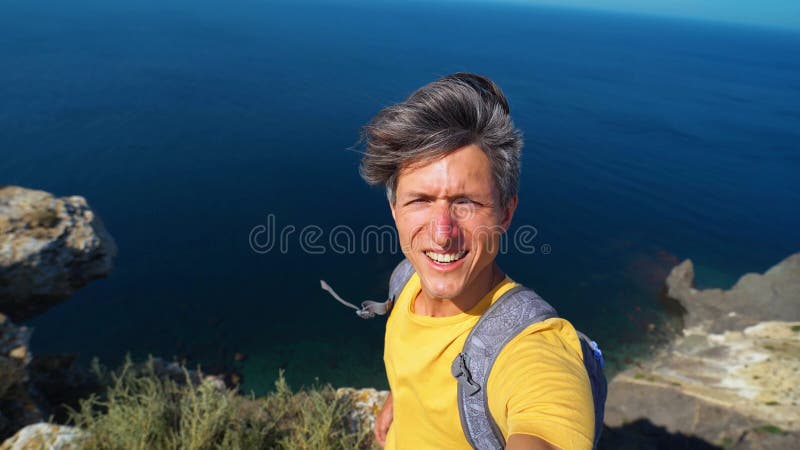 Hombre guapo que tiene videochat usando smartphone al aire libre compartiendo viajes metrajes