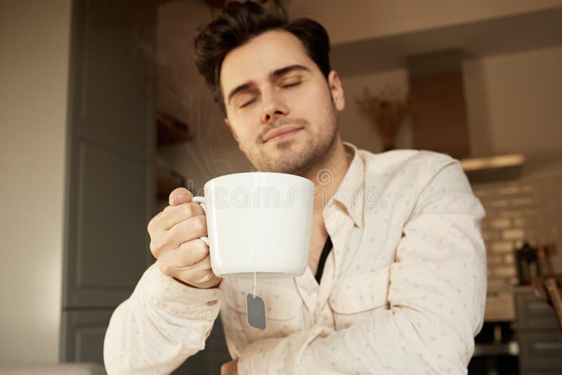 Hombre hermoso atractivo que sostiene la taza de café blanca en casa foto de archivo Hombre hermoso atractivo que sostiene la taza de café blanca en casa foto de archivo