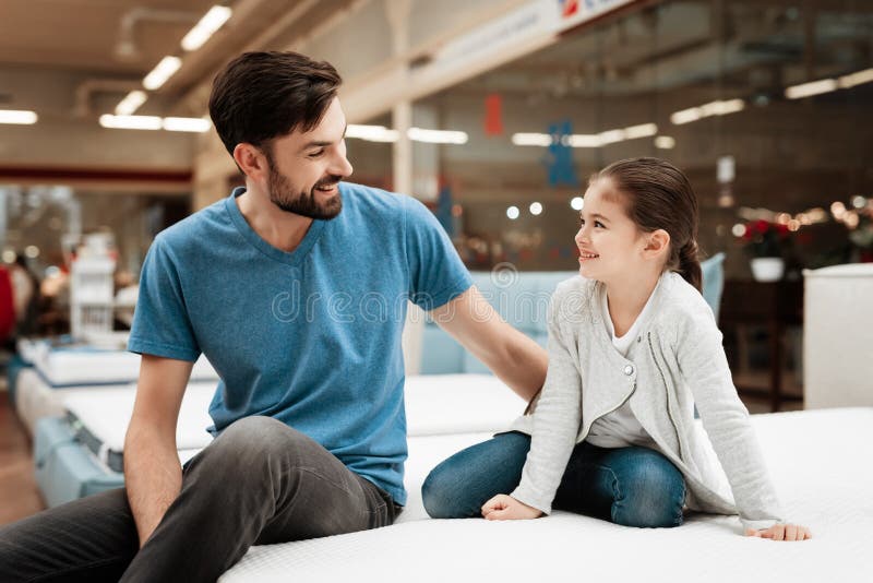 Hombre hermoso barbudo con la hija que se sienta en el colchón Elegir el colchón en tienda fotos de archivo libres de regalías Hombre hermoso barbudo con la hija que se sienta en el colchón Elegir el colchón en tienda fotos de archivo libres de regalías