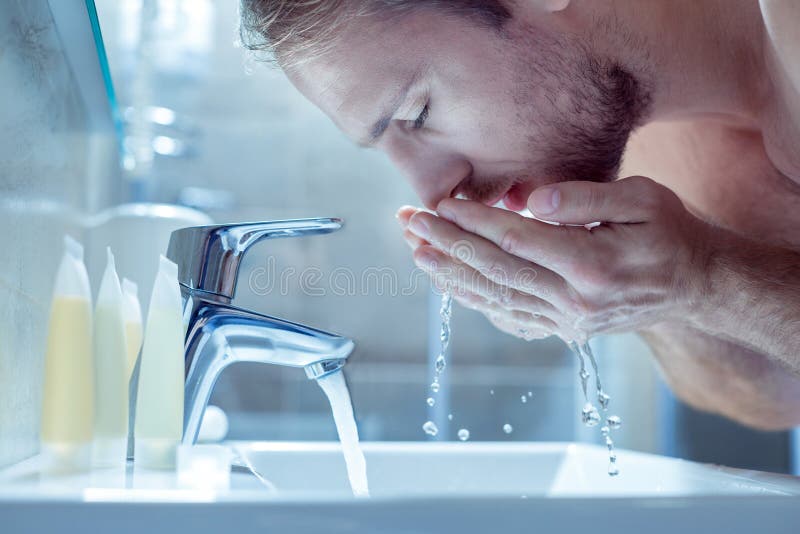 Hombre hermoso barbudo que se lava la cara por la mañana en cuarto de baño ligero foto de archivo libre de regalías Hombre hermoso barbudo que se lava la cara por la mañana en cuarto de baño ligero foto de archivo libre de regalías