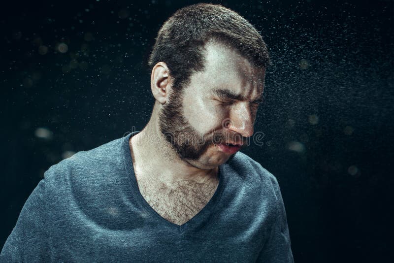Hombre hermoso joven con la barba que estornuda, retrato del estudio fotografía de archivo Hombre hermoso joven con la barba que estornuda, retrato del estudio fotografía de archivo