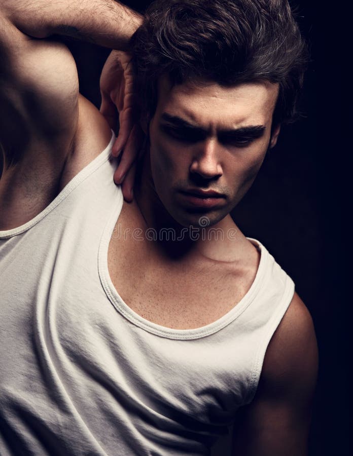Hombre hermoso joven fuerte atractivo que presenta en la camiseta blanca en el drak s fotos de archivo libres de regalías